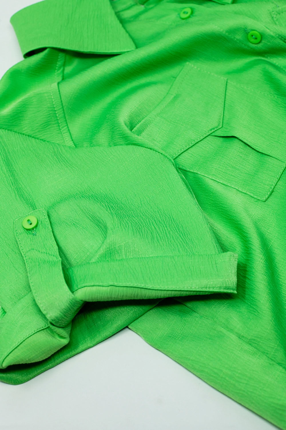 Groene korte satin blouse met borstzakken en koordjes onderaan