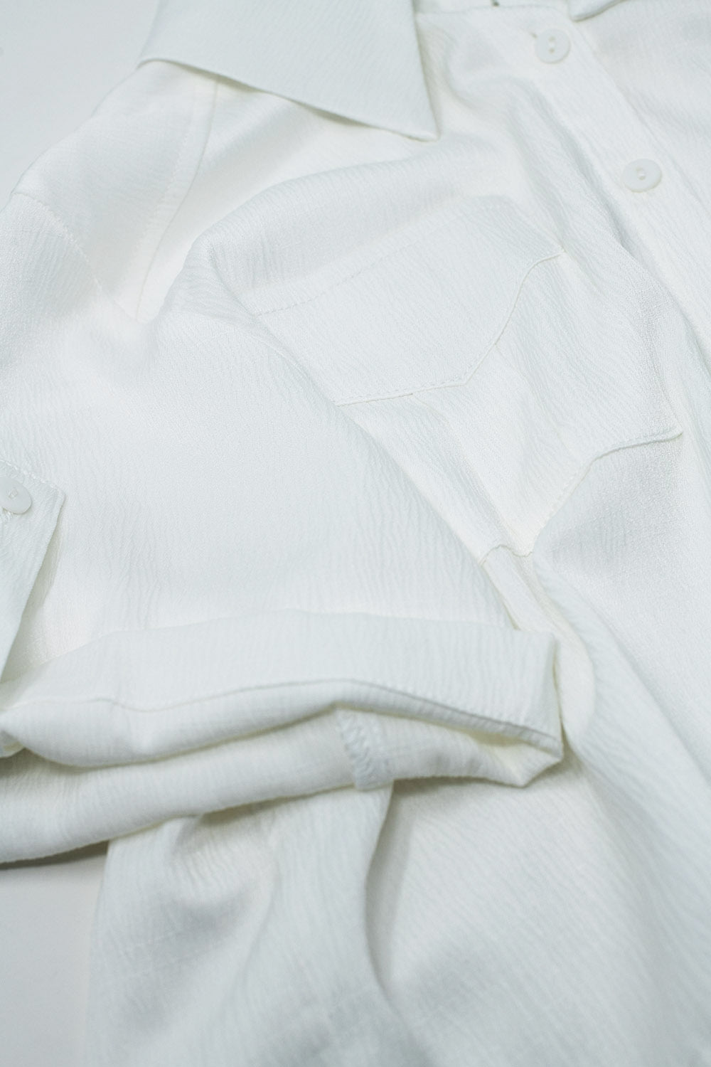 Witte korte satin blouse met borstzakken en koordjes onderaan
